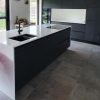 Herentals moderne zwarte keuken met wit composiet werkvlak en zijkanten
